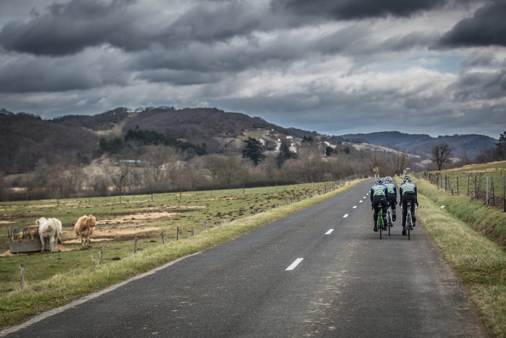 Winter miles, summer smiles - cyclists riding towards grey clouds