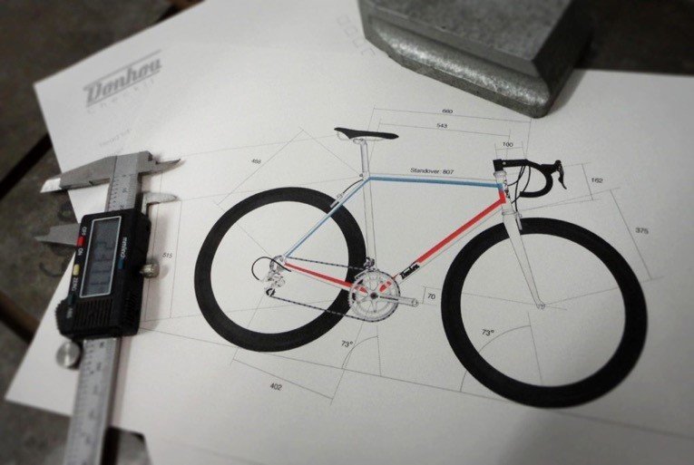 Are they using callipers to measure an annotated computer drafting of a bicycle?