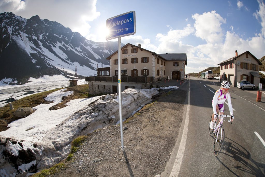Exploring the cyclist’s paradise of Davos-Klosters. Cyclist rides past Fluelapass signpost. 