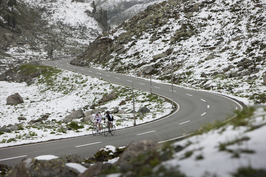 Exploring the cyclist’s paradise of Davos-Klosters. Cyclists ride a snowy mountain road. 