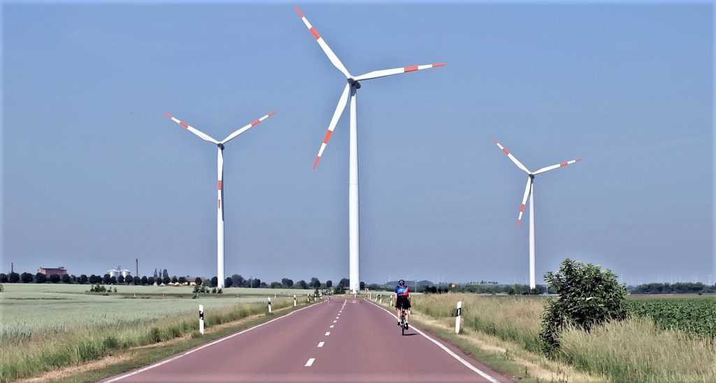 How much difference does a headwind make when cycling? A cyclist rides towards three wind turbines