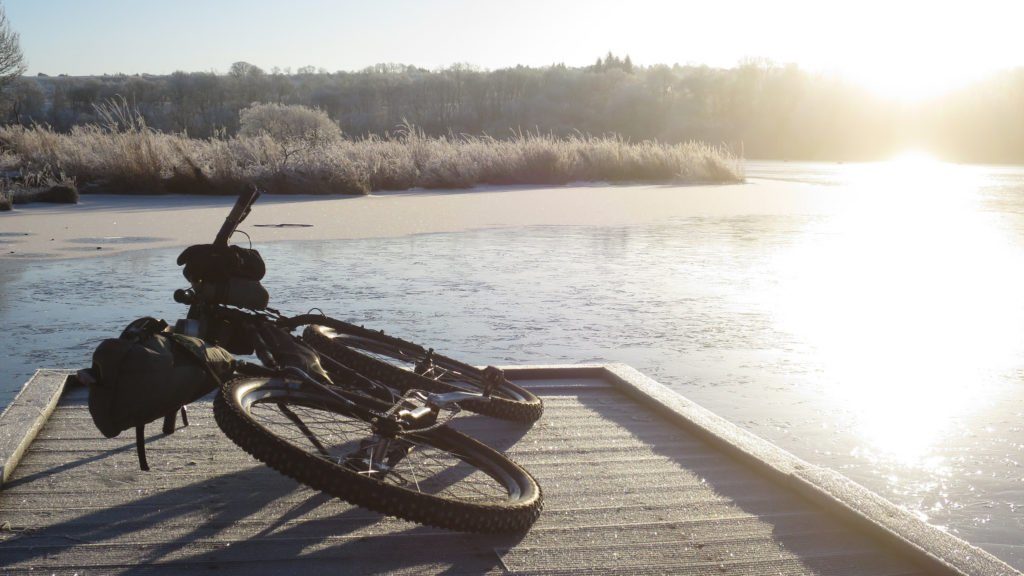 Cycle touring in Scotland, mountain bike beside frozen-lake - Bikepacking scotland