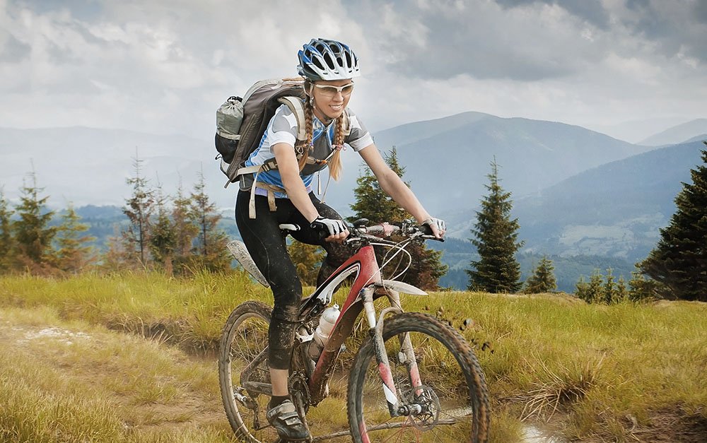 Woman mountain-bike riding on ridge with Carpathian Mountains