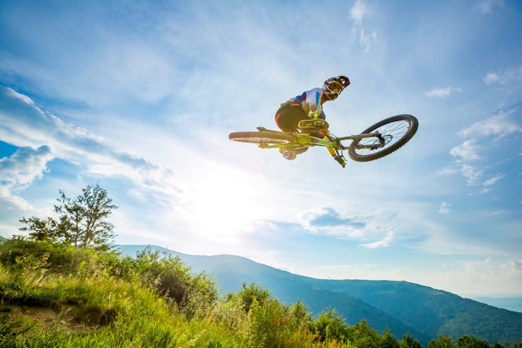 Professional rider is jumping on the bicycle, with background of blue sky. Sunny summer day, freeriding mountain bike disiciplines