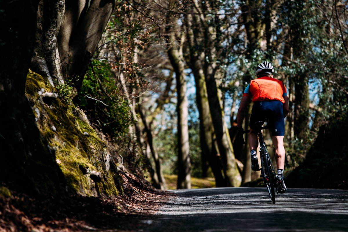 sportspursuit man cycling on winding forest road 