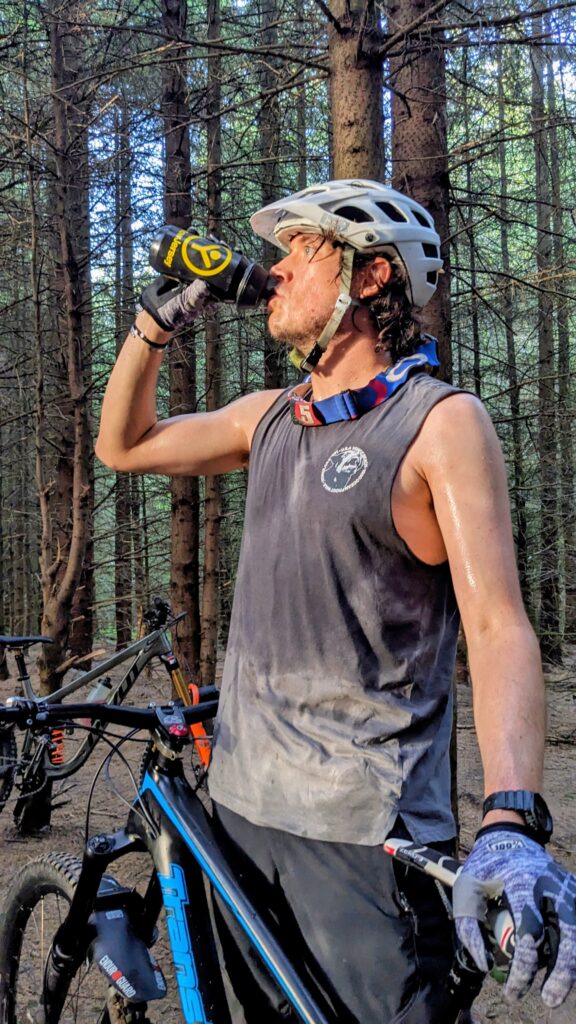 a mountain biker drinking from a bottle in the woods